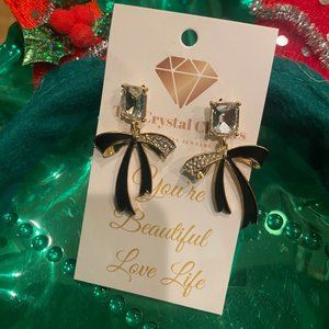 Ladies holiday earrings made of large square cut crystals and black enamel bows.